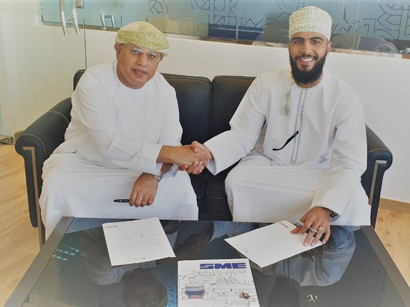 Two Omani businessmen shaking hands after signing a business agreement, representing a successful partnership